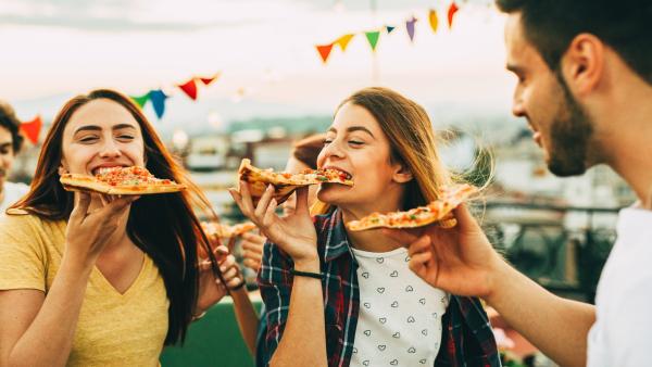 3 young adults eating pizza at a festival