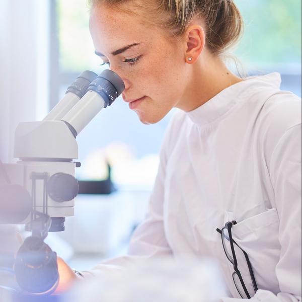 research and development scientist looking through a microscope